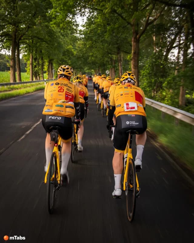 Team Rynkeby-ryttere på en lang række ned ad en allé